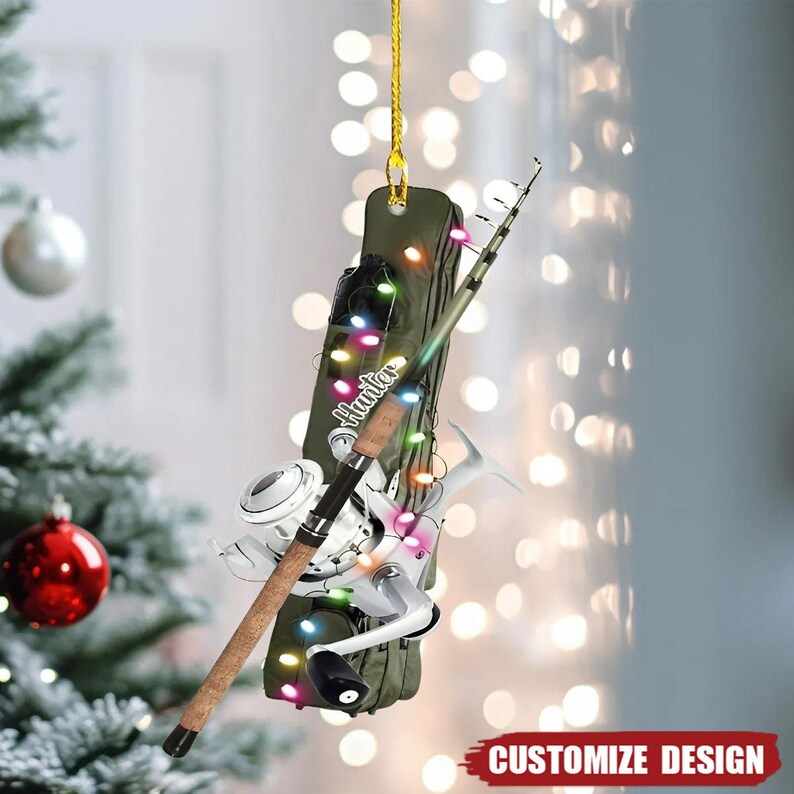 May include: A fishing-themed Christmas ornament with a fishing rod, reel, and a green case. The ornament is decorated with colourful lights and the word "Hunter". The bottom right corner has the text "CUSTOMIZE DESIGN".