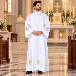 May include: A white liturgical alb featuring a high collar, long sleeves, and gold embroidered cross motifs on the cuffs and lower hem. The garment is floor-length with a structured fit and a vertical placket detail at the center of the chest.