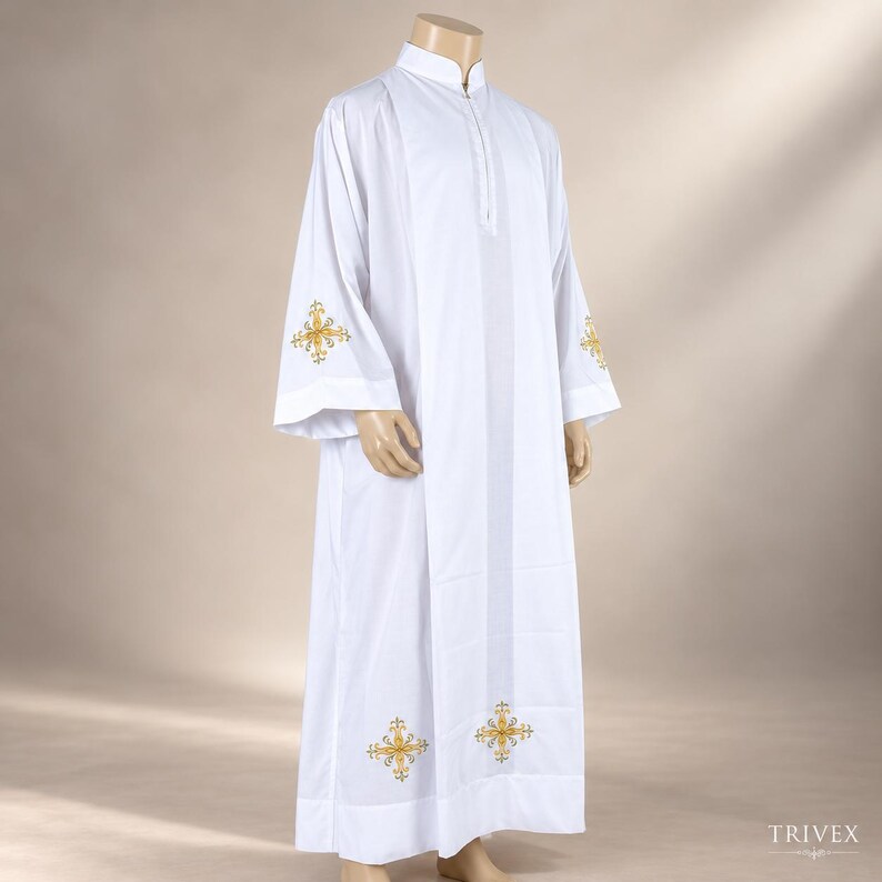 May include: A white liturgical alb featuring a high collar and long sleeves. The garment is decorated with gold-colored embroidered cross motifs positioned on the lower sleeves and near the bottom hem. The fabric is smooth and opaque.