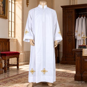 May include: A white liturgical alb featuring a mandarin collar with a front zipper closure. The garment includes gold embroidered cross motifs on the lower front panels and on each sleeve cuff, displayed on a mannequin in a church setting.