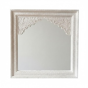 Könnte beinhalten: Quadratischer weißer Spiegel mit gewölbtem Oberteil und aufwendigen geschnitzten floralen Details. Der Rahmen hat ein mehrschichtiges Design mit komplizierten Mustern. Der Spiegel ist ein dekoratives Wohnaccessoire.