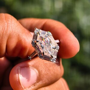 An image of the NovaLux Jewels Dutch marquise ring held up to demonstrate scale and its unique, slenderizing effect on the hand. The geometric stone creates a sophisticated focal point, while the dainty pave band adds to the modern minimalist aesthetic. Shimmering light reflections suggest a high-value anniversary or wedding gift that combines timeless elegance with contemporary design.