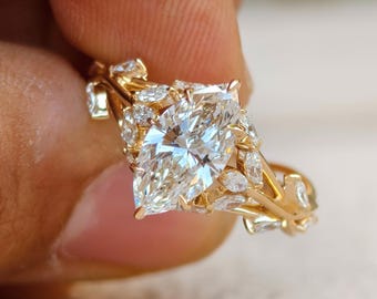 Könnte beinhalten: Ein goldener Ring mit einem großen Diamanten im Marquiseschliff als Mittelpunkt. Der Ring ist mit kleineren Diamanten im Marquiseschliff und aufwendigen Goldfiligran-Details verziert. Das Design des Rings ist elegant und auffällig.