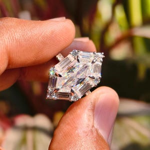 A variation of the Dutch marquise ring shown in 14k yellow gold to highlight the "Golden Glamor" trend. The warm gold metal enhances the bright white brilliance of the D-color moissanite, creating a regal and nostalgic aesthetic. The image focuses on the rich, golden hue of the band and its elegant, handcrafted curves as they meet the shimmering geometric center stone.