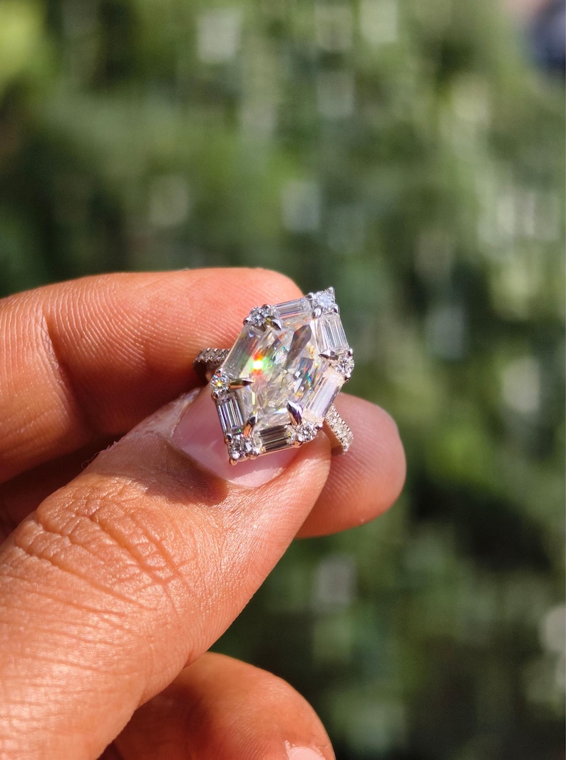 May include: A large, sparkling engagement ring with a unique, geometric-cut center stone. The ring features a halo of smaller, rectangular-cut diamonds around the main stone and along the band, creating a brilliant display of light.