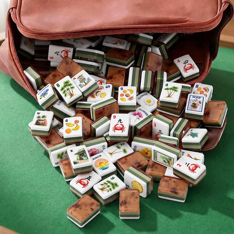 May include: A set of rectangular mahjong tiles with white faces featuring colorful illustrations of crabs, palm trees, fruits, and flowers, and brown, wood-grain patterned backs, spilling out of an open brown leather-like zippered carrying case.