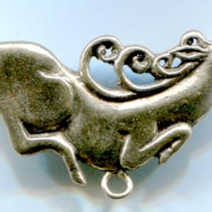 Puede incluir: Un colgante de plata en forma de ciervo estilizado con detalles intrincados. El ciervo está saltando y tiene un anillo unido a su parte inferior.