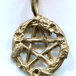 Könnte beinhalten: Ein goldfarbener Anhänger mit einem fünfzackigen Stern, oder Pentagramm, umgeben von einem Kranz aus stilisierten Zweigen.