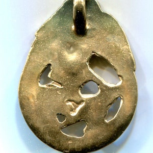 May include: Gold pendant with a loop at the top and a design of cut-out shapes. The pendant is oval shaped and has a smooth, shiny surface.