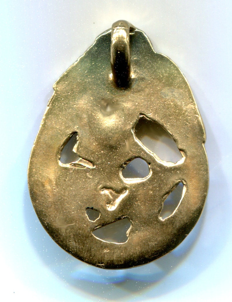 May include: Gold pendant with a loop at the top and a design of cut-out shapes. The pendant is oval shaped and has a smooth, shiny surface.