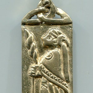 Puede incluir: Colgante plateado con forma rectangular y un lazo en la parte superior. El colgante presenta un relieve detallado de una figura sosteniendo un bastón. La parte superior del colgante tiene un diseño de nudo celta.