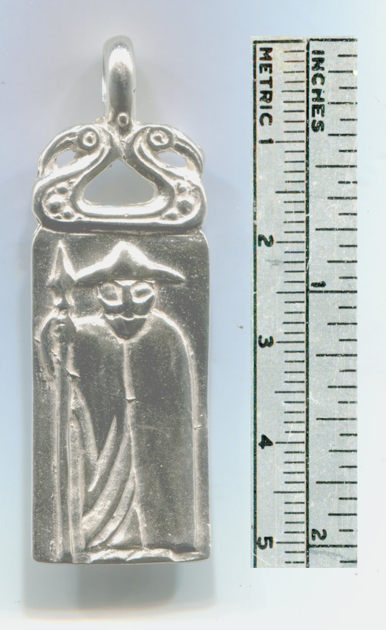 May include: Silver pendant depicting a figure in a hooded cloak holding a spear. The pendant is approximately 2 inches tall and has a detailed design.