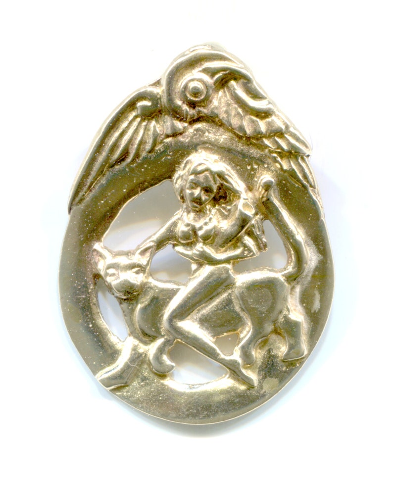 May include: A gold-toned pendant featuring a woman riding a mythical creature with wings. The pendant is intricately detailed and has a cutout design.