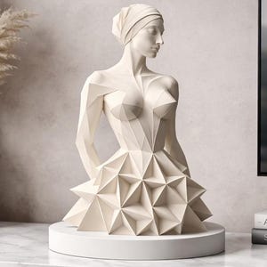 Könnte beinhalten: Eine weiße, geometrische Skulptur einer Frau, mit Kopfbedeckung und einem Kleid mit dreieckigem Muster. Die Skulptur steht auf einem weißen, kreisförmigen Sockel, was auf ein modernes Kunstwerk hindeutet.