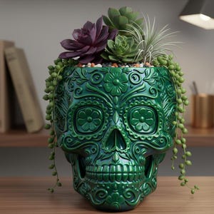Pu&ograve; includere: Un vaso verde a forma di teschio con intricati disegni floreali, riempito con piante grasse e piante ricadenti. Il vaso lucido &egrave; posto su una superficie di legno, creando un elemento decorativo unico.