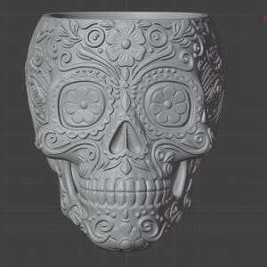 Pu&ograve; includere: Un vaso grigio a forma di teschio decorativo con intricati motivi floreali e a spirale. Il vaso presenta grandi orbite oculari con disegni floreali e una mascella dettagliata. Il design generale ricorda le celebrazioni del Giorno dei Morti.