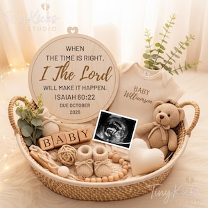 May include: A wicker basket holds baby items, including a onesie with "Baby Williamson" printed on it, a teddy bear, and wooden blocks spelling "BABY." A wooden plaque with a heart cutout and text from Isaiah 60:22 is also present, along with baby booties and an ultrasound image.
