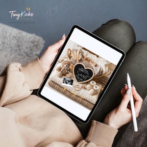 May include: A digital tablet displays a pregnancy announcement. The announcement includes a teddy bear, baby shoes, a sonogram, and a heart-shaped chalkboard that reads "We've been keeping a little secret. Due June 2024."