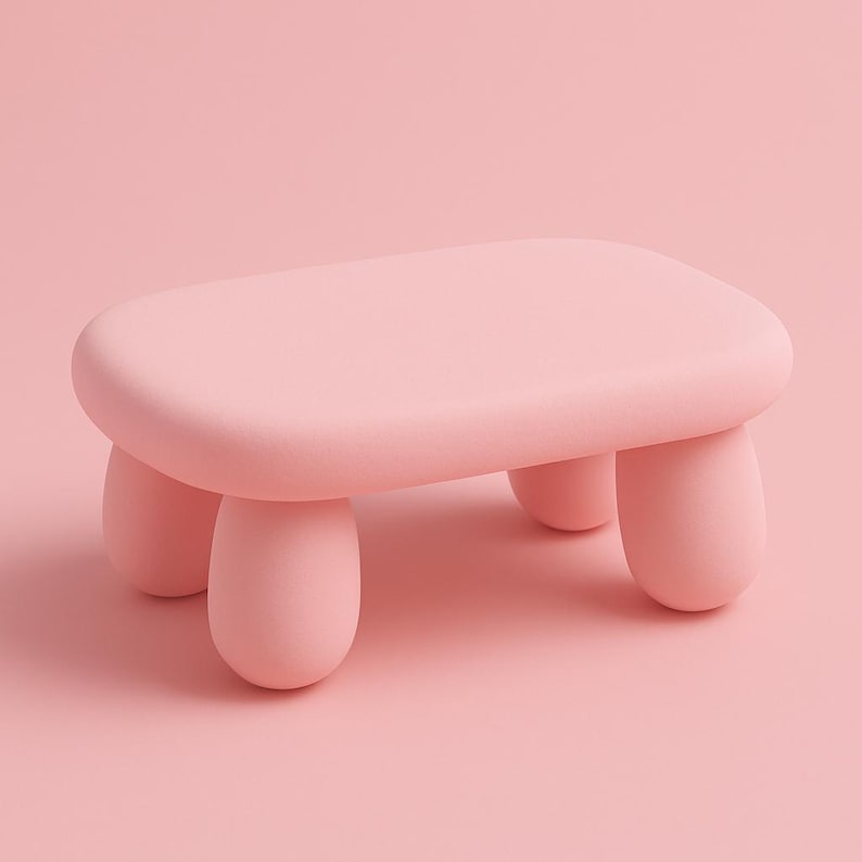 May include: A small, pastel pink stool with a rounded rectangular top and four short, rounded legs. The stool is a solid color and has a smooth, matte finish. The design is minimalist and modern, suitable for various interior styles.