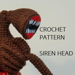 May include: A brown crochet Siren Head figure with a large head and two siren-like speakers. The mouth is open, revealing white teeth and red gums. The text "CROCHET PATTERN SIREN HEAD" is visible.