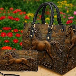 Könnte beinhalten: Ein braunes Lederhandtaschen- und passendes Geldbörsen-Set. Beide Artikel zeigen ein detailliertes Relief eines galoppierenden Pferdes. Die Handtasche hat schwarze Griffe und goldfarbene Beschläge. Die Geldbörse hat eine Handschlaufe und der Name "EMILY" ist sichtbar.