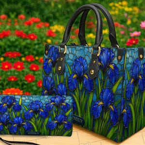 May include: A handbag and wallet set featuring a stained-glass style design of blue irises. The handbag has black handles and gold-colored hardware. The wallet has a wrist strap. The background is a blurred image of a flower garden.