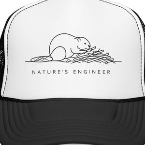 以下が含まれることがあります： 白と黒のトラッカーキャップ。枝を使って作業するビーバーの黒い線画が描かれています。グラフィックの下には、すっきりとしたサンセリフ体で「NATURE'S ENGINEER」という文字が記されています。前面は白、背面は黒いメッシュ素材です。