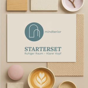 May include: A flat lay composition on a beige surface. A card with the text "STARTERSET" and "mindterior" is the focal point. Other elements include a coffee cup with latte art, a pink sphere, and material samples of wood and tile.