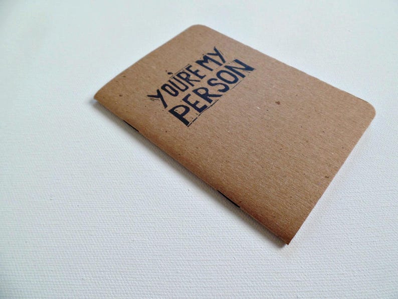 Op de afbeelding: Een bruin notitieboekje met de tekst "YOU'RE MY PERSON" in zwart gedrukt.