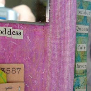 May include: Close-up of a mixed media artwork with a vibrant pink background. The word "Goddess" is spelled out in cut-out letters. Other text includes "tender," "Queen," and "fair." A decorative element with rhinestones is visible.