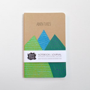 May include: A brown notebook with a green, blue, and white mountain illustration on the cover. The notebook says "Adventures" and "Notebook/Journal" on the front. The notebook is blank, has 64 acid-free pages, and an inner pocket.