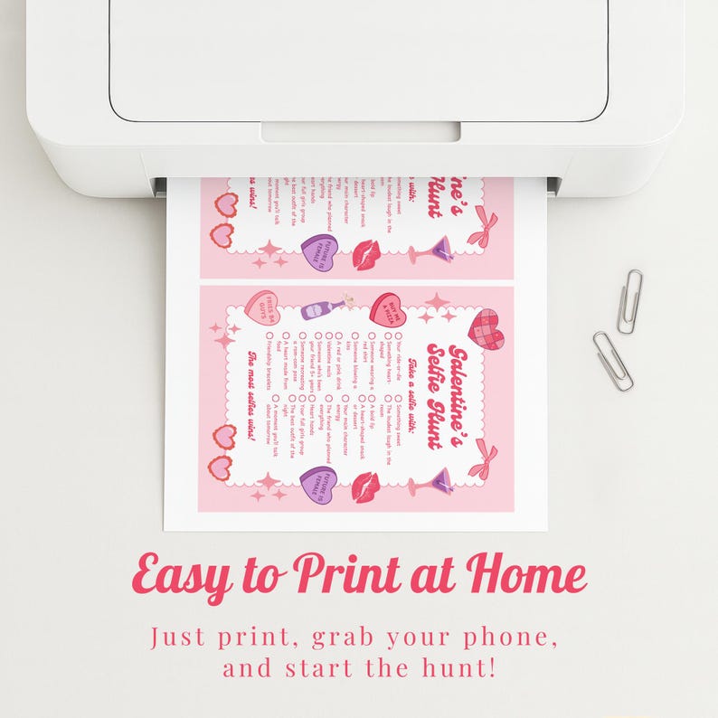May include: A pink Valentine's Selfie Hunt printable sheet is being printed from a white printer. The sheet has a decorative border with hearts, lips, and cocktail glasses. The text "Easy to Print at Home" is at the bottom.