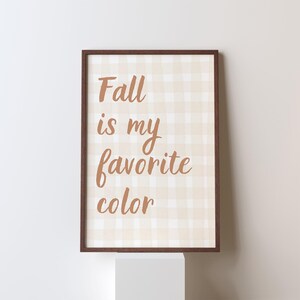 Può includere: Una stampa incorniciata con la scritta "Fall is my favorite color" in un carattere marrone caldo. Lo sfondo presenta un motivo a quadretti beige e bianco e la cornice è marrone scuro.