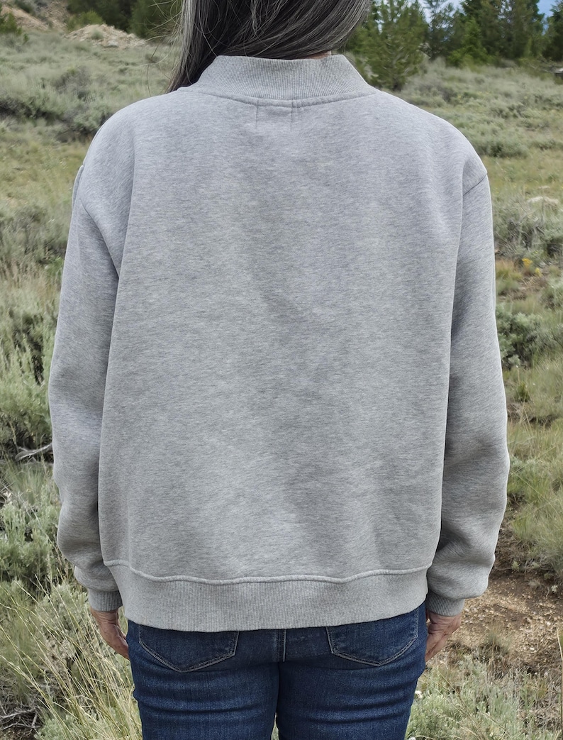 Back view of a gray oversized mockneck sweatshirt showing the relaxed fit and length.
