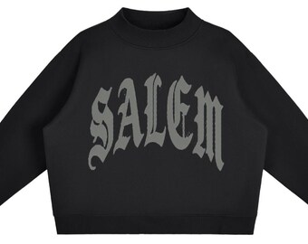 May include: A black long-sleeve sweatshirt featuring a mock neck collar and ribbed cuffs. The word SALEM is printed across the chest in a large, arched, gothic-style font in a dark grey colour, contrasting against the solid black fabric.
