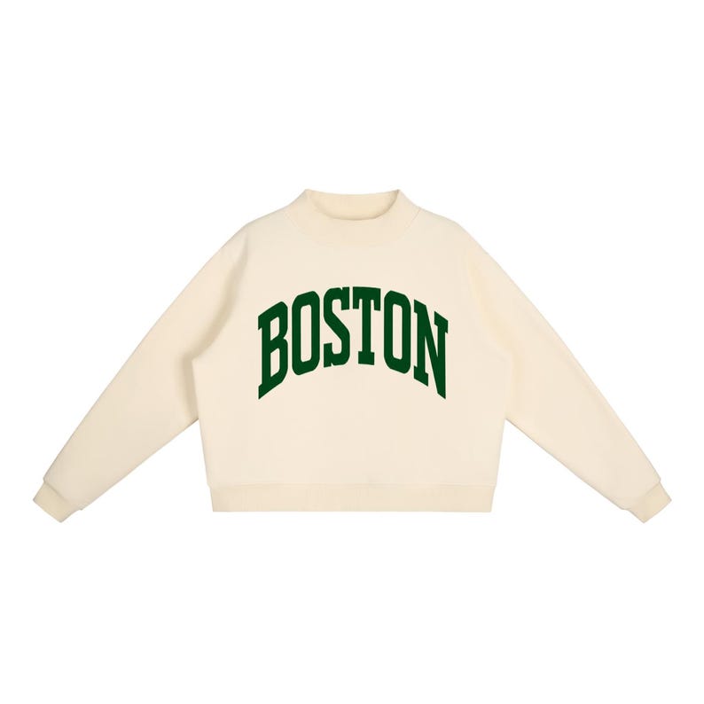 Op de afbeelding: Een cr&egrave;mekleurig sweatshirt met lange mouwen, een opstaande kraag en geribbelde boorden. Het woord BOSTON staat in een donkergroen, gebogen lettertype in collegestijl op de borst gedrukt. Het kledingstuk heeft een rechte zoom en lange mouwen.