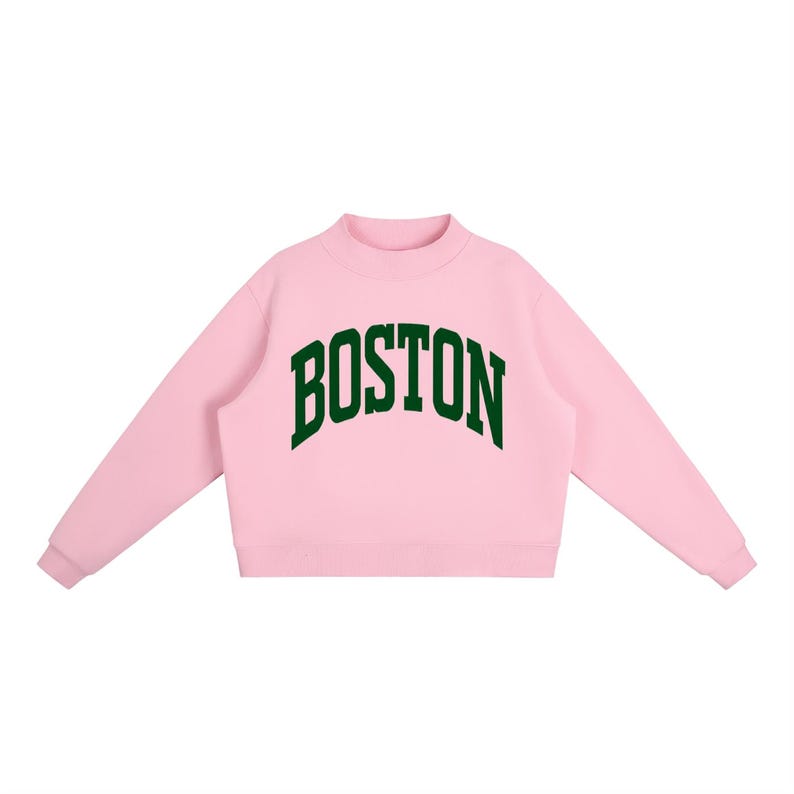 Op de afbeelding: Een lichtroze sweatshirt met lange mouwen, een opstaande kraag en geribbelde boorden. Het woord BOSTON is in een donkergroen, gebogen lettertype in collegestijl in het midden op de borst gedrukt. Het kledingstuk heeft een rechte zoom.