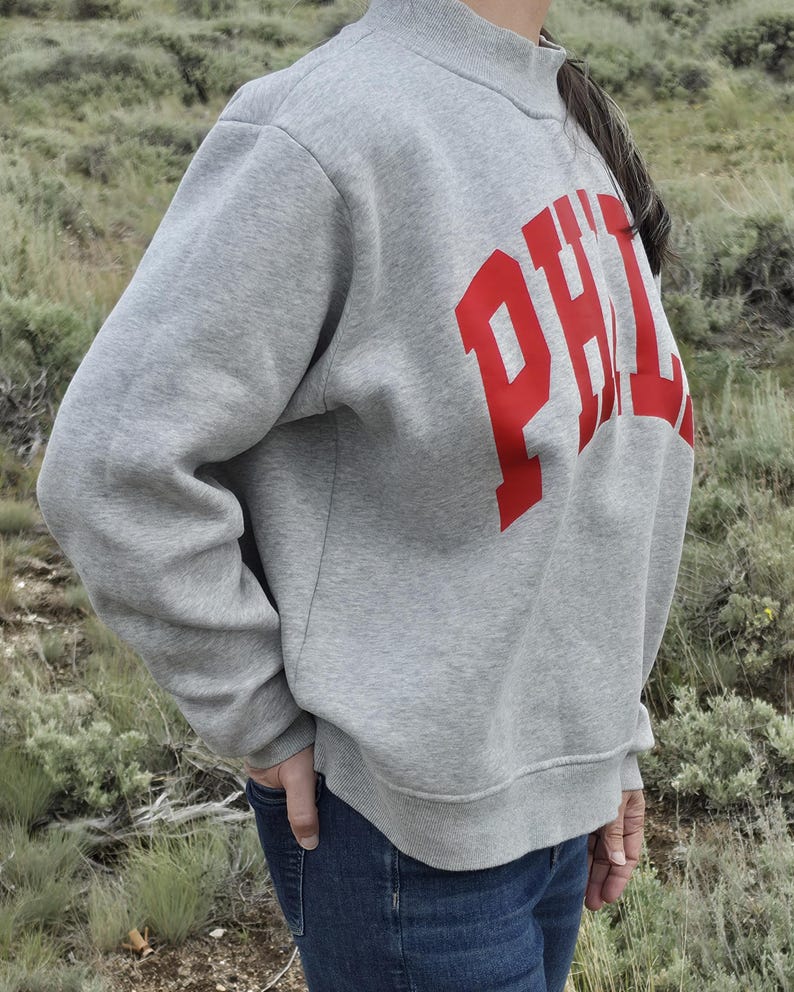 Side view of a gray oversized PHILA mockneck sweatshirt showing the relaxed oversized fit.