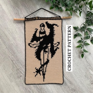 May include: A beige crochet wall hanging with a black silhouette design, suspended from a wooden dowel. The design features a figure on a horse. The text "CROCHET PATTERN" is printed vertically on the right side.