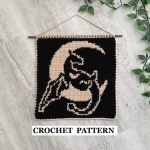 Könnte beinhalten: Schwarzer und beigefarbener Wandbehang aus Häkelarbeit mit einem Halbmond und einer stilisierten Figur. Das quadratische Stück ist an einem Holzstab mit einer beigefarbenen Kordel aufgehängt. Der Text "CROCHET PATTERN" steht unten.