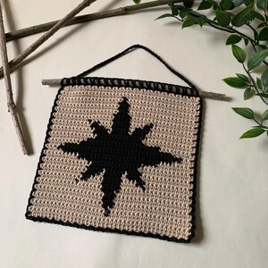 Modern crochet wall hanging pattern featuring a bold black eight-pointed star on a neutral background. This is a digital PDF pattern for instant download, not a finished product.