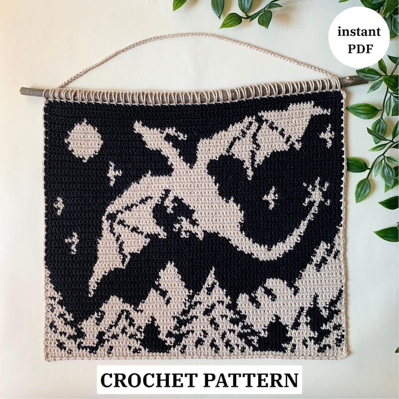 May include: A black and beige crochet wall hanging featuring a dragon silhouette against a night sky with a moon and stars. The bottom of the piece depicts a forest. The text "CROCHET PATTERN" is at the bottom.