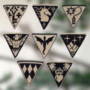 May include: A collection of seven handmade, triangular crochet patches. Each patch features a unique black design on a tan background, including a key, a unicorn, and a winged figure. The patches are bordered with a black crochet stitch.