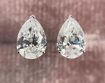Può includere: Un paio di orecchini a lobo con taglio a goccia e pietre sfaccettate trasparenti montate su metallo color argento lucido. Ogni orecchino è fissato con una montatura a tre griffe, che esalta la brillantezza delle pietre a forma di goccia.