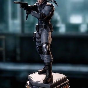 Peut inclure: Une figurine de collection détaillée représentant un soldat tactique en tenue de combat grise, bottes noires et bandeau, tenant une arme de poing noire avec silencieux. La figurine repose sur une plateforme hexagonale à rayures de danger.