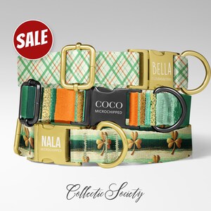 May include: Three dog collars with gold-colored hardware and patterned fabric. One collar has a green plaid pattern, another has orange and green stripes, and the third has shamrock designs. The collars are labeled with the names "BELLA", "COCO", and "NALA".