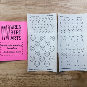 Peut inclure: Quatre feuilles de papier blanc avec des dessins au trait noir de différents motifs et designs. Les motifs comprennent des chats, des flèches et des lignes. Les feuilles sont étiquetées avec le site Web wrenbirdarta.com et le hashtag #wrenmend.