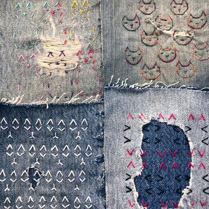 May include: A close-up of a denim patchwork quilt featuring various coloured thread embroidery. The quilt is made from several different pieces of denim fabric, each with a unique pattern. The embroidery is in the shape of cats, triangles, and other geometric shapes.