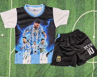 May include: A two-piece soccer uniform set featuring a jersey and shorts. The jersey has a black front with a blue and white design and a picture of a soccer player. The shorts are black with the name "MESSI" and the number "10".