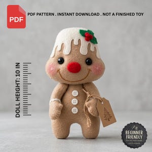 May include: A tan felt gingerbread doll with white icing, a red nose, and three white buttons. The doll features a green holly leaf with red berries on its head and holds a brown tag with a tree icon. Text indicates a 10 inch height.